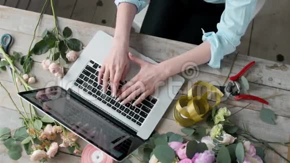 俯视办公桌台工作空间笔记本电脑玫瑰花束花艺工作空间带笔记本电脑女性视频的预览图