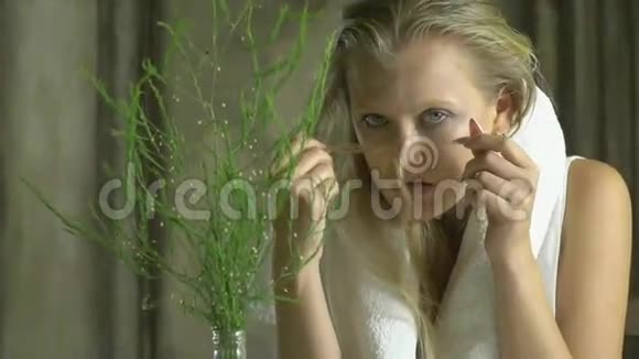 一个被毛巾覆盖的女人坐在有绿色的花瓶旁边视频的预览图