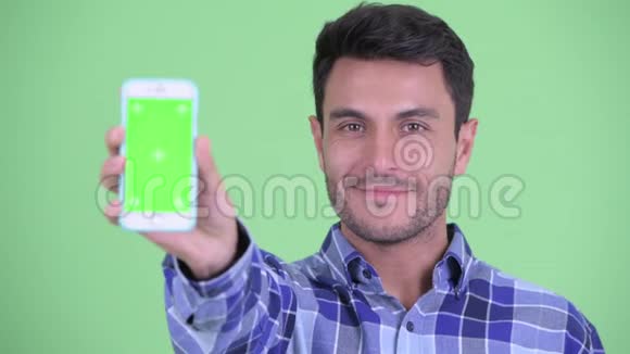 一位年轻快乐的西班牙裔男子展示电话视频的预览图