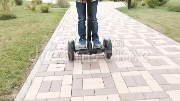 无法辨认的男孩正在家附近骑着陀螺滑板车腿部特写视频的预览图