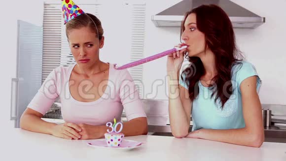 女人在厨房里的朋友旁边吹着派对喇叭视频的预览图