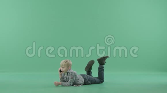 孩子躺在地板上用智能手机说话视频的预览图