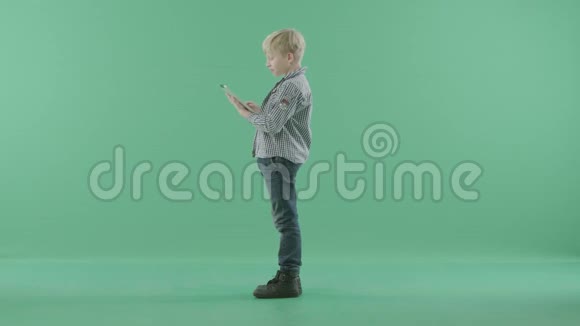 可爱的男孩站在侧面手里拿着一台平板电脑视频的预览图