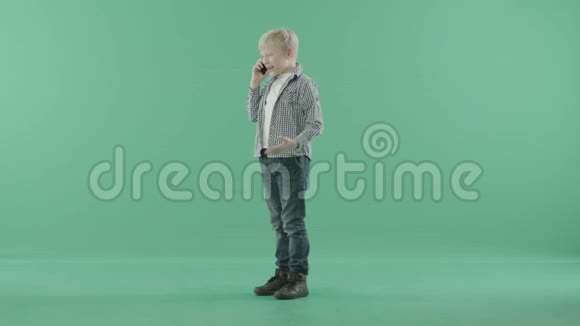 小男孩在绿色屏幕上的电话里有感情地交谈视频的预览图