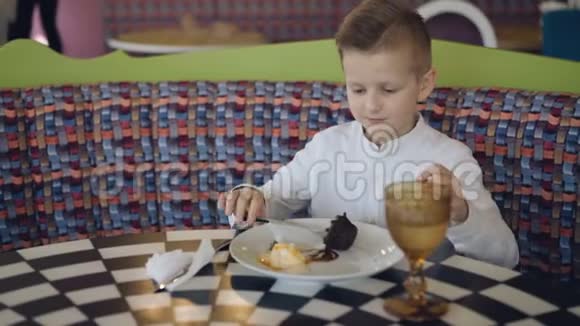 英俊的微笑男孩在咖啡馆里吃美味的甜点4K视频的预览图