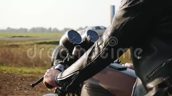 一名男子戴着黑色头盔和皮夹克骑摩托车在沥青道路上的侧面景色晴天视频的预览图