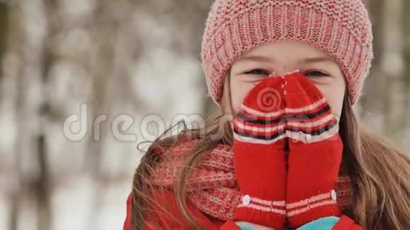冬天在树林里长雀斑的年轻女学生的肖像2他用手套把手暖和起来视频的预览图