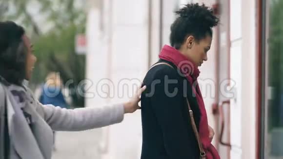 两个漂亮的混血女人带着购物袋在商场附近的大街上相遇视频的预览图
