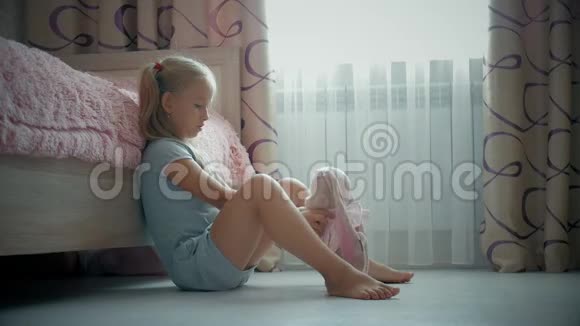 一个漂亮的小女孩和一只玩具兔子在家里穿裙子家庭关系孩子拥抱可爱的玩具视频的预览图