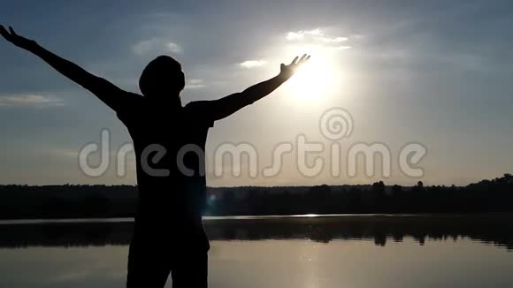 日落时分年轻人在湖岸上快乐地举起双手动作缓慢视频的预览图
