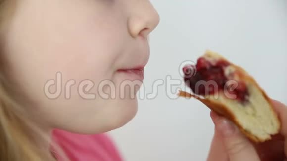 金发女孩在白色背景特写镜头上吃樱桃派视频的预览图