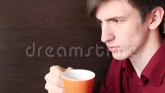 一个年轻人带着一个橙色的杯子到嘴里做了两个小嘴唇视频的预览图