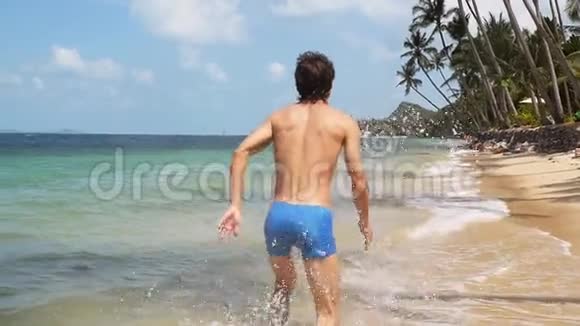 在阳光明媚的日子里年轻人在海滩上奔跑在小水滴上溅起海浪慢慢慢慢视频的预览图