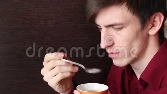 一个年轻人用嘴舔一茶匙然后把它放在桌子上视频的预览图