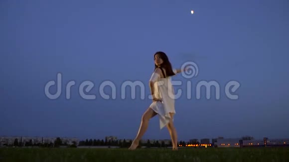 一个穿着白色连衣裙的日本女孩靠在腿上举起她的手慢镜头拍摄视频的预览图