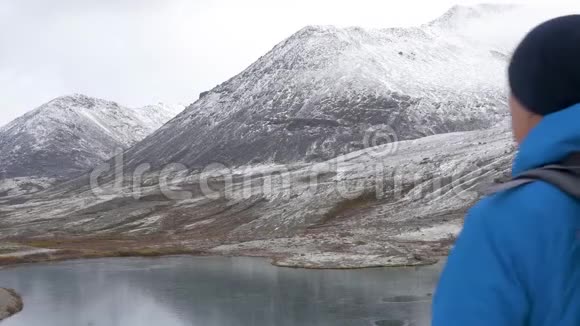一个带背包的人在山里旅行他的周围是美丽的山脉和清澈的湖泊他的照片视频的预览图