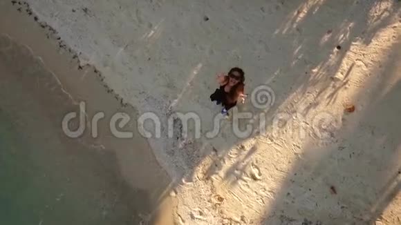 快乐的女孩长着长发在海滩上用手抓住四架直升机无人机安全落地高清航拍以上自拍镜头视频的预览图