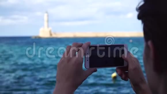年轻女子在欧洲一座城市的灯塔里用智能手机拍照视频的预览图