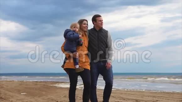 寒冷的一天父母带着小女儿在海边散步视频的预览图