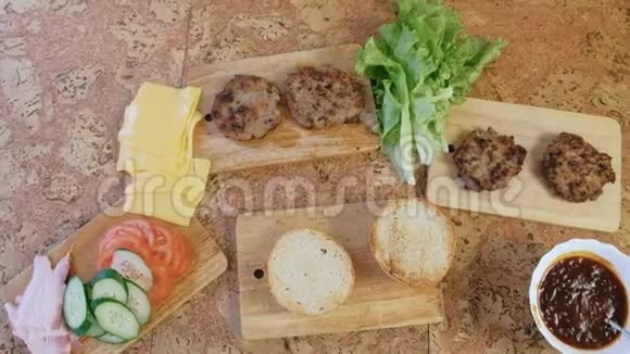准备汉堡的产品面包西红柿黄瓜小切片奶酪沙拉酱汁桌子上的培根顶级视频的预览图