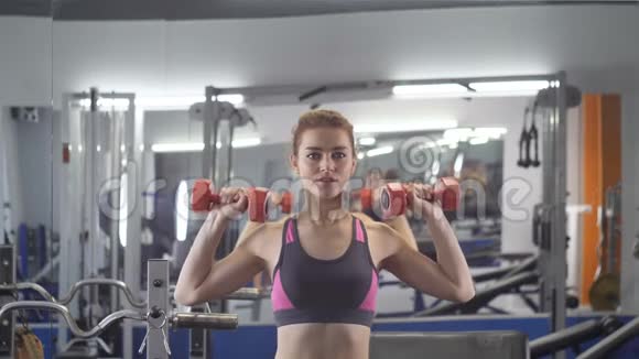 年轻漂亮的运动女孩用哑铃做压肩运动在运动健身房锻炼视频的预览图
