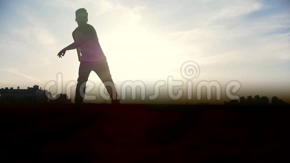 慢动作年轻的雄性跑酷特技跳投者在太阳面前表演惊人的翻转动作视频的预览图