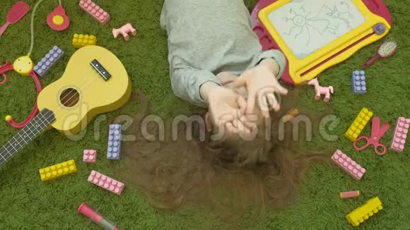 小女孩笑着躺在绿色的背景下俯视视频的预览图