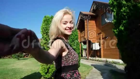 跟着我微笑女孩的肖像穿着五颜六色衣服的年轻女人把男朋友拉到湖边的房子里视频的预览图