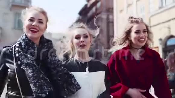 三个时髦的女人聚集在一起沿着街道笑着交流时尚美丽视频的预览图