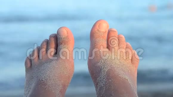 两只脚在海浪前撒满了沙子视频的预览图