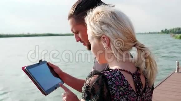 在湖边使用平板电脑的男孩和女孩在湖边使用平板电脑ipad视频的预览图