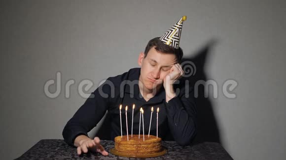 一个人独自庆祝节日他独自坐在一张桌子旁桌上放着蛋糕和蜡烛视频的预览图