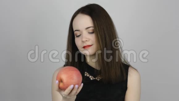 美丽的年轻女子吃着粉红色的苹果微笑着视频的预览图