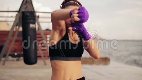 慢动作镜头年轻女子用手裹着紫色的拳击磁带看镜头视频的预览图