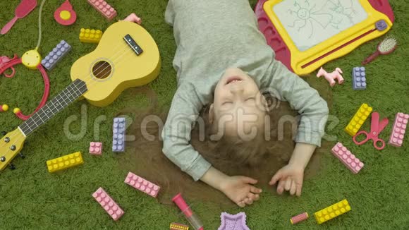 小女孩笑着躺在绿色的背景下俯视视频的预览图