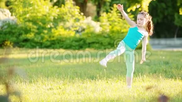 活泼的小女孩在夏天公园的草地上做一个手推车视频的预览图