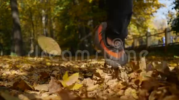 秋天雄性的腿在黄色的落叶上行走人从树叶中走过地毯特写镜头慢动作视频的预览图