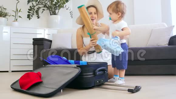 4k视频可爱的幼儿男孩帮助妈妈把东西装在手提箱里视频的预览图