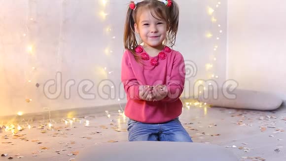 小女孩坐在地板上手里拿着节日的五彩纸屑视频的预览图