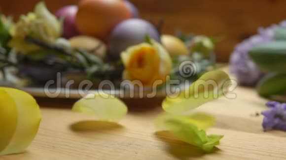 玫瑰花瓣落在桌子上背景是彩色复活节彩蛋视频的预览图