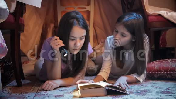 两个女孩在帐篷里用手电筒看书4k视频视频的预览图