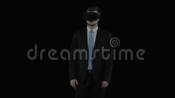 穿着黑色西装的年轻人戴着虚拟现实眼镜观察着照片视频的预览图