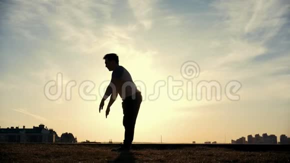 慢动作年轻的雄性跑酷花样跳投者在太阳面前表演令人惊奇的翻转动作视频的预览图