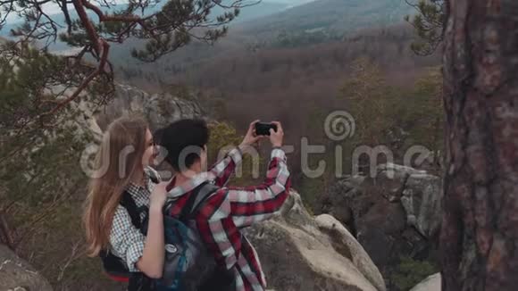 鸟瞰一个年轻可爱的人在山顶自拍微笑笑美丽的景色视频的预览图