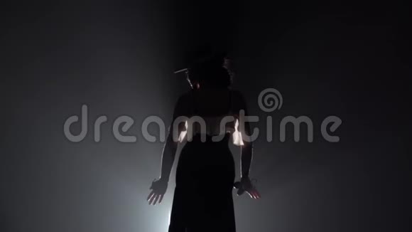 弗拉门戈女孩戴着帽子跳舞手里拿着石膏跳舞从后面的光烟雾背景慢动作视频的预览图