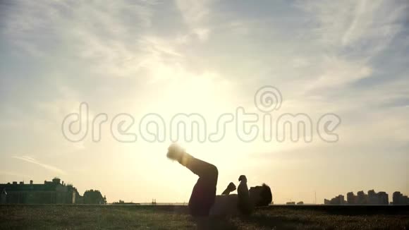 慢动作年轻的雄性跑酷花样跳投者在太阳面前表演令人惊奇的翻转动作视频的预览图