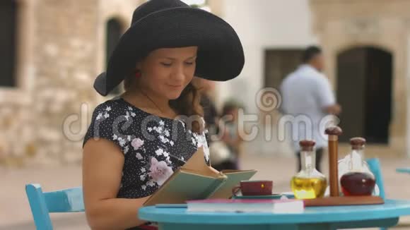 年轻的女作家在笔记本上做笔记享受户外咖啡馆的休息视频的预览图