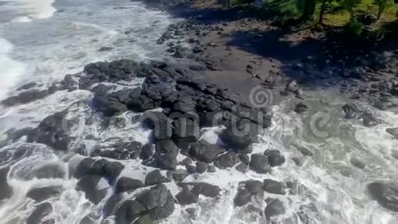 在巴厘岛Soka海滩绕着黑色的岩石拍打着海浪视频的预览图
