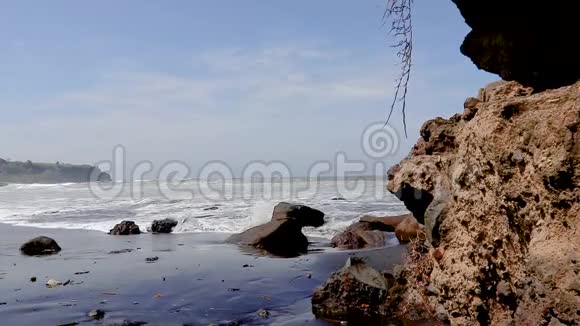 从大海到海滩的海浪从巴厘岛海滩的岩石后面带走视频的预览图
