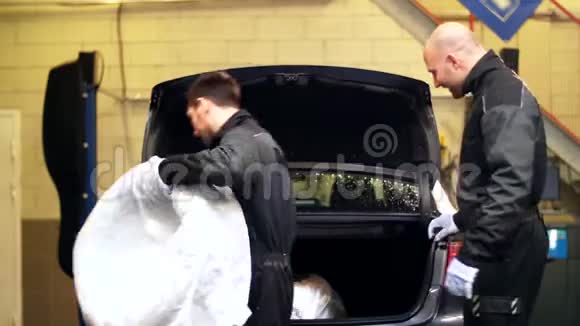 维修时从汽车后备箱取出轮胎的技师视频的预览图